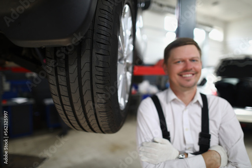 Smiling repairman man in auto repair shop near car lift