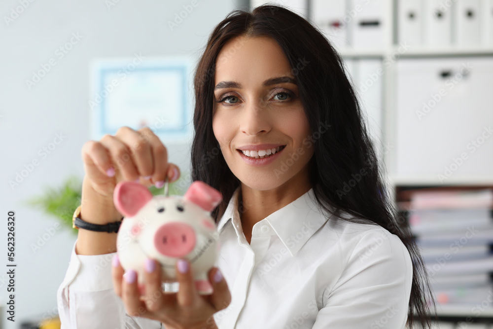 Portrait of smiling woman throwing coin into piggy bank Portrait of smiling woman throwing coin into piggy bank