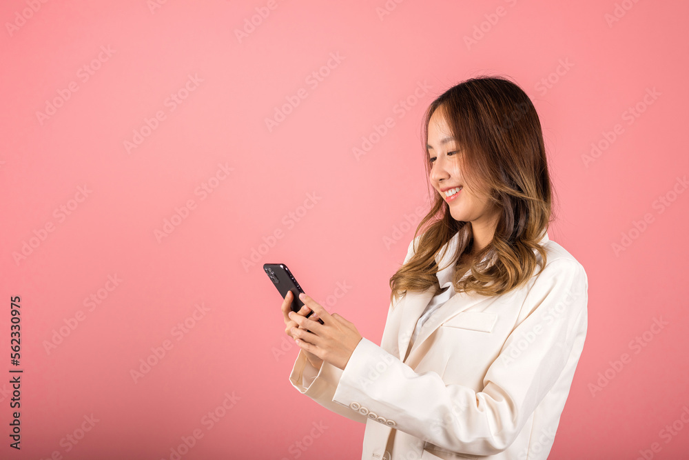 Female surprised and sms chatting internet online on smartphone studio shot isolated on pink background, Happy Asian portrait beautiful cute young woman teen smiling excited hold smart mobile phone Female surprised and sms chatting internet online on smartphone studio shot isolated on pink background, Happy Asian portrait beautiful cute young woman teen smiling excited hold smart mobile phone