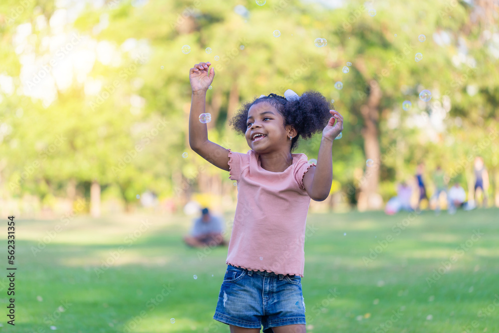 Happy kid girl playing with soap bubbles. Active child playing outdoor in the park. Happy kid girl playing with soap bubbles. Active child playing outdoor in the park.