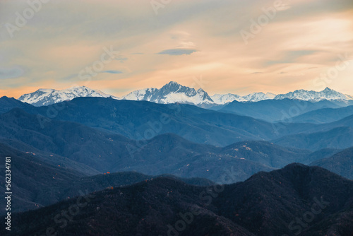 Stunning view of the ridge of mountain peaks from a height. Mountain peaks of the Caucasus on a sunny day. A magnificent mountain range with high snow-capped peaks. View from a height of 1000 m. © Vit-Vit
