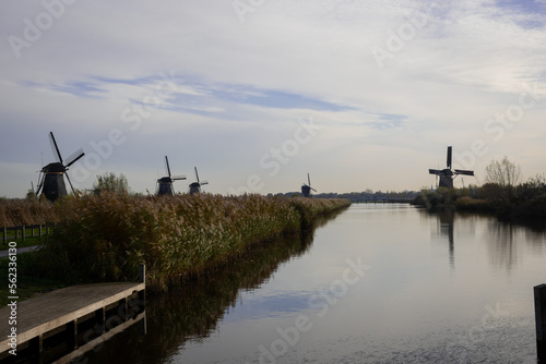 iconic windmills in Kinderdijk Netherlands next to canal waterway flood management. Landmark buildings originally made to pump water out of low land polder to preserve land reclaimed from the sea
