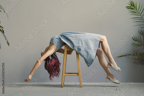 Lying down on chair lady posing scenic photography. Picture of woman in linen dress with wall, houseplants on background. High quality wallpaper. Photo concept for ads, travel blog, magazine, article