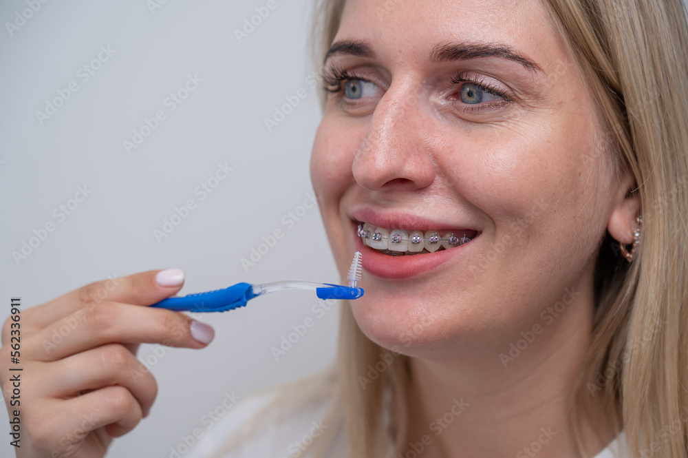Caucasian woman cleaning her teeth with braces using a brush. Caucasian woman cleaning her teeth with braces using a brush.