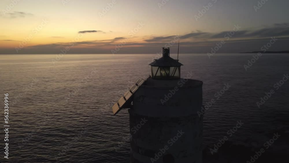 Striking Lighthouse shining light at sunset, aerial drone circling around Striking Lighthouse shining light at sunset, aerial drone circling around