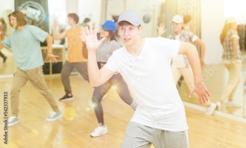 Group of active teens rehearsing modern dance in studio.