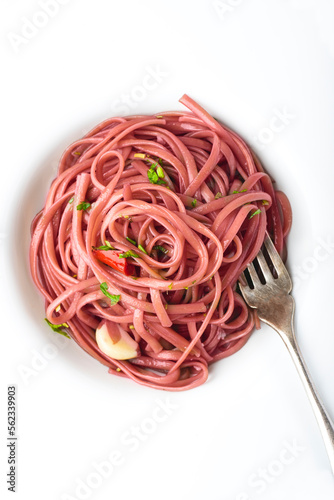  Spaghetti pasta stewed on red wine with bay leaves, garlic and parsley, white table. Unusual, regional and simple Italian pasta recipes (original Pasta with Barolo wine). Close up