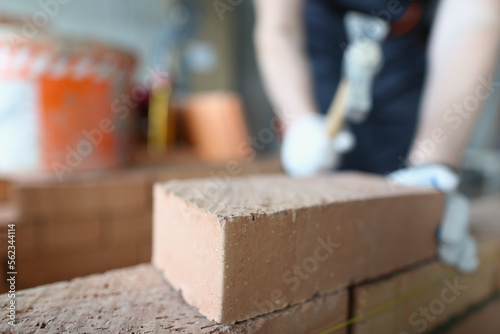 Closeup of industrial bricklayer laying bricks at construction site