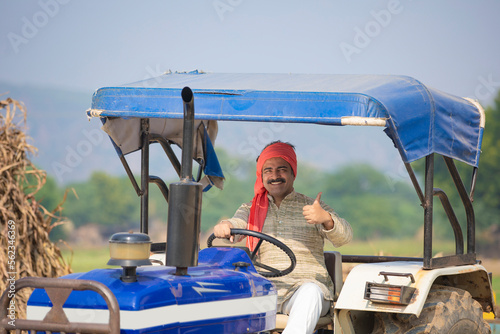 Indian farmer sitting on tractor and showing thumps up at agriculture field. © PRASANNAPIX