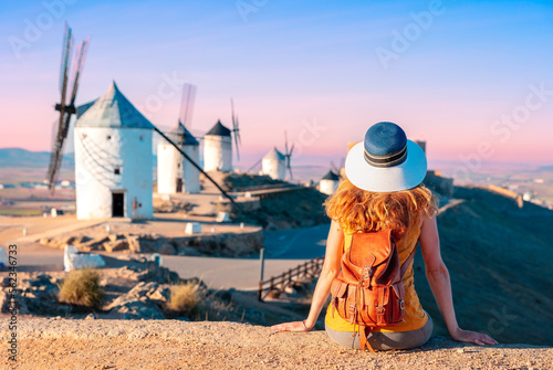 Woman tourist looking at windmills with castle, Consuegra, Castile-La Mancha, Spain
