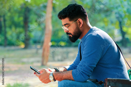 Indian man using smartphone at park.