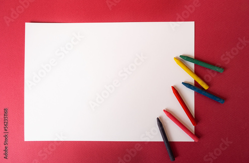 White sheet of paper with wax crayons on a magenta-colored background