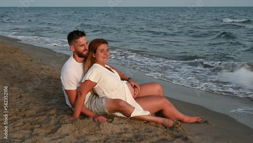 pregnant woman with her companion sitting in front of the sea