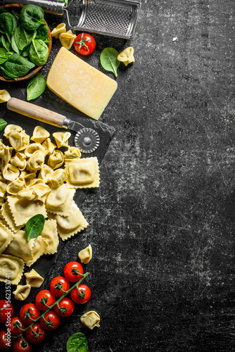 An assortment of different types of raw pasta with cheese, tomatoes and herbs.
