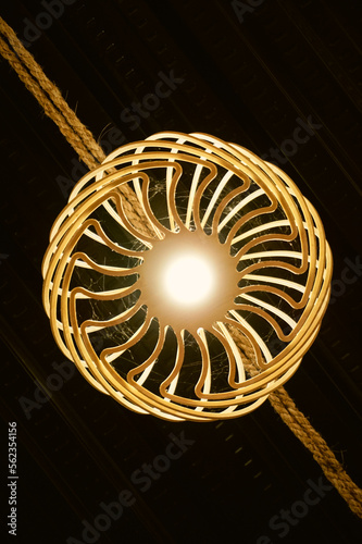 Bottom view of yellow bulb with rattan woven ornament that hanging in the rope. Inspiration for modern lighting and home decoration. Rattan chandelier for vintage and abstract background. Wicker Lamp.