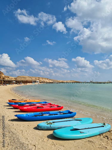 Canvas Print Colored windsurfing boards and canoes lie on the sea beach