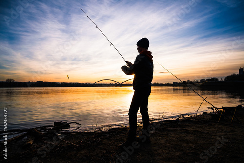 Teenage boy is fishing on river bank. Boy is fishing in sunset.