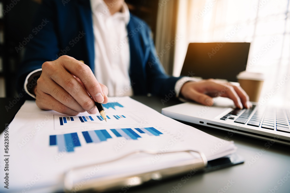 business documents on office desk with laptop and smart phone and graph business diagram and man working in morning light. business documents on office desk with laptop and smart phone and graph business diagram and man working in morning light.