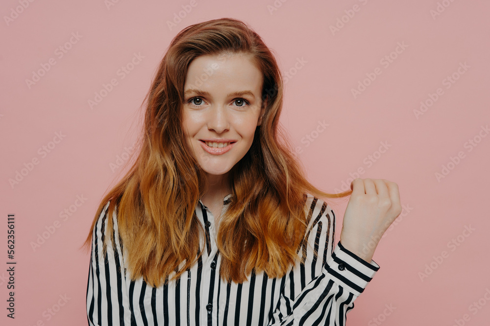 Attractive smiling young girl looking at camera holding hair strand Attractive smiling young girl looking at camera holding hair strand