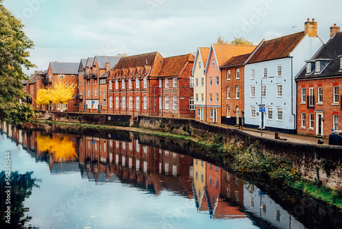 Street view with colorful brick houses near river in the small english town Norwich, England in autumn. Townhouses Buildings At Waterfront. Suburb Houses, Residential Building Near River In Europe. photo