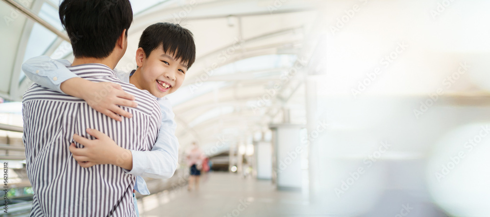 Happy cheerful Asian little boy running to his father at the railway or sky train station after his father returned from the traveling trip. Happy Asian family father and son concept. Happy cheerful Asian little boy running to his father at the railway or sky train station after his father returned from the traveling trip. Happy Asian family father and son concept.