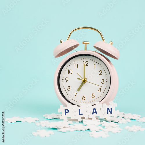 Alarm clock with the word plan standing on puzzle pieces, brainstorming for new ideas, planning new goals and resolutions