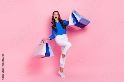Full body length size photo of overjoyed shopaholic lady wear blue blouse fist up hold bags new cheap clothes isolated on pink color background photo
