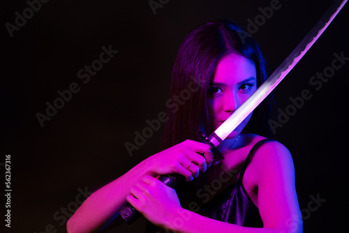 Beautiful asian woman with katana sword in neon lights. Copy space. © Dmytro
