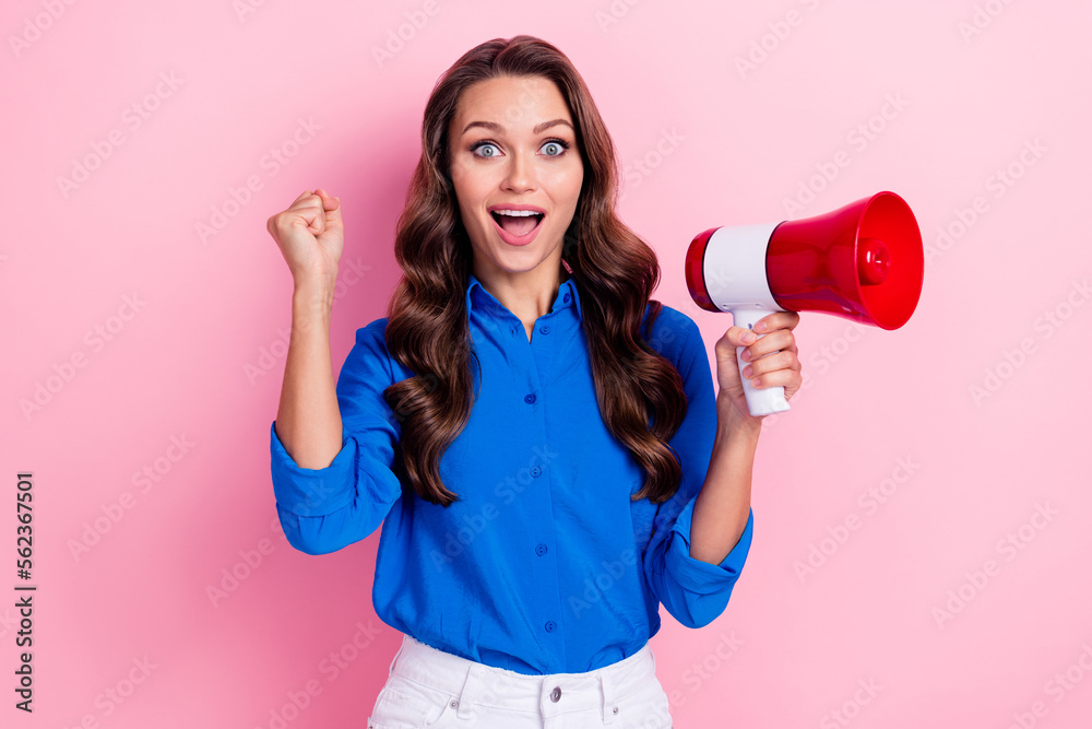 Photo of impressed ecstatic woman with curly hairdo dressed blue blouse hold megaphone clench fist isolated on pink color background Photo of impressed ecstatic woman with curly hairdo dressed blue blouse hold megaphone clench fist isolated on pink color background