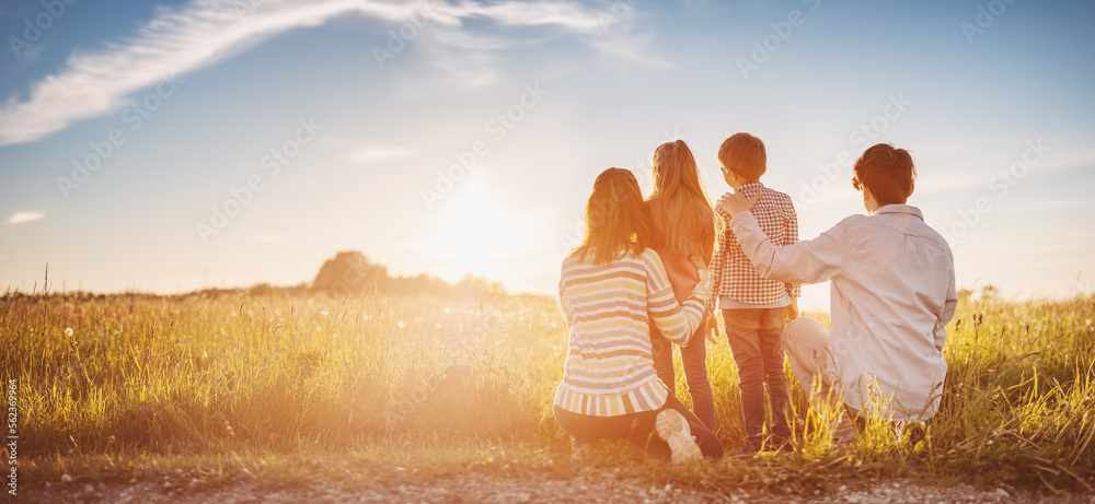 Family standing on the sunset on the field in natural park. - obrazy, fototapety, plakaty 