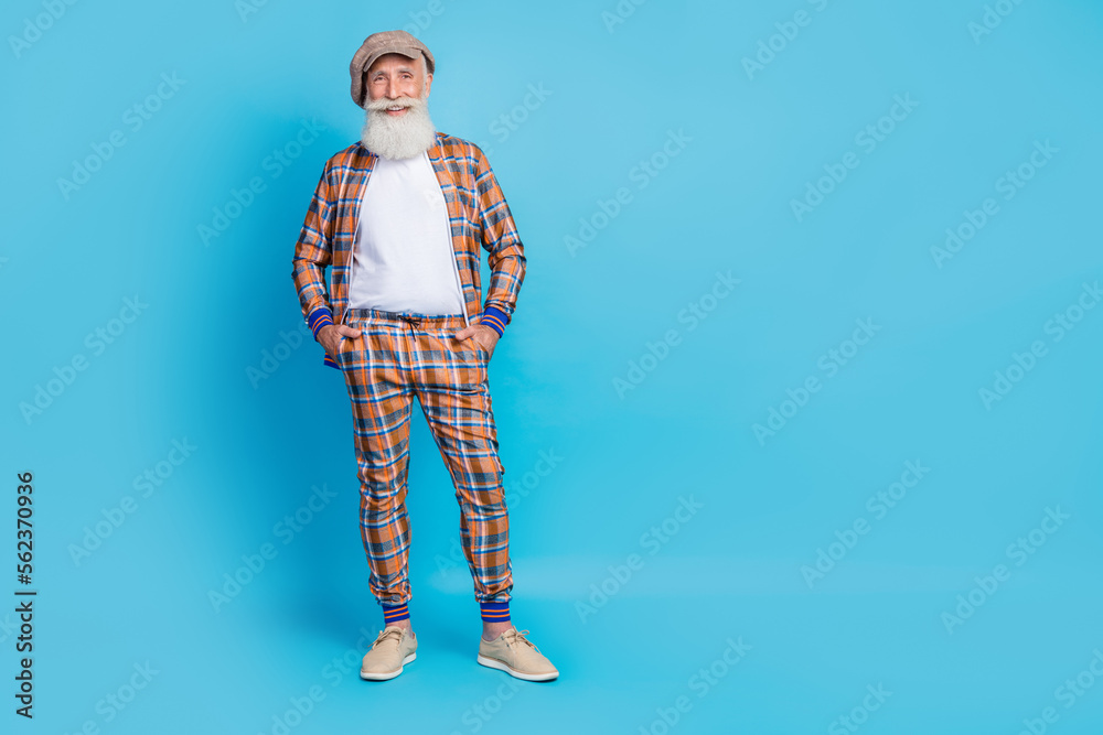 Fototapeta premium Full length photo of cheerful stylish macho dressed fashionable plaid outfit hand pocket empty space isolated on blue color background