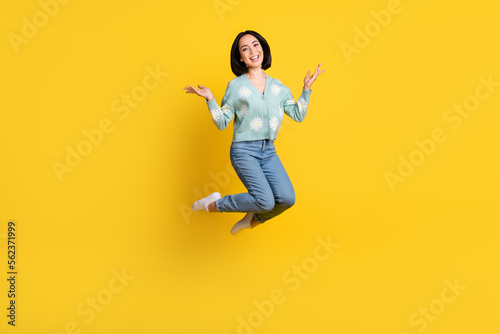 Full size photo of satisfied adorable woman bob hairstyle dressed blue pullover flying raise palms up isolated on yellow color background