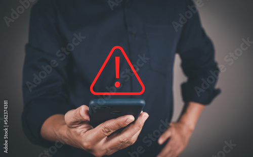 Businessman or User, programmer, developer using smart phone with triangle caution warning sign for notification error and maintenance warning and safety concept.