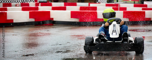 Brave young racer at high speed passes the turn of the karting track on a racing car. Young karting racer on the circuit in a protective helmet