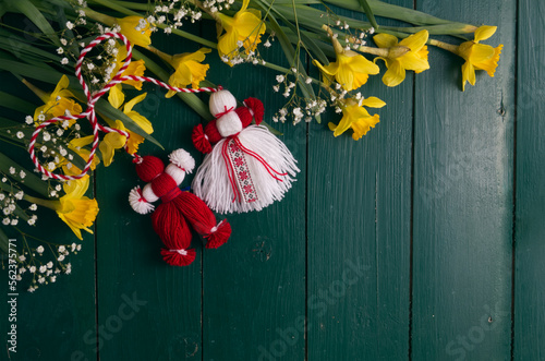 Martenitsa, Martisor, on a green wooden table framed with yellow daffodils