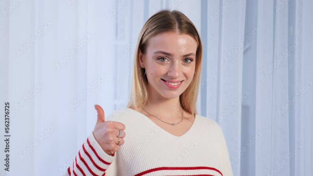 Confident happy smiling young girl teen student wears casual cool sweater showing thumb up. Satisfied woman looking at camera giving positive service or goods recommendation, approval symbol. Confident happy smiling young girl teen student wears casual cool sweater showing thumb up. Satisfied woman looking at camera giving positive service or goods recommendation, approval symbol.
