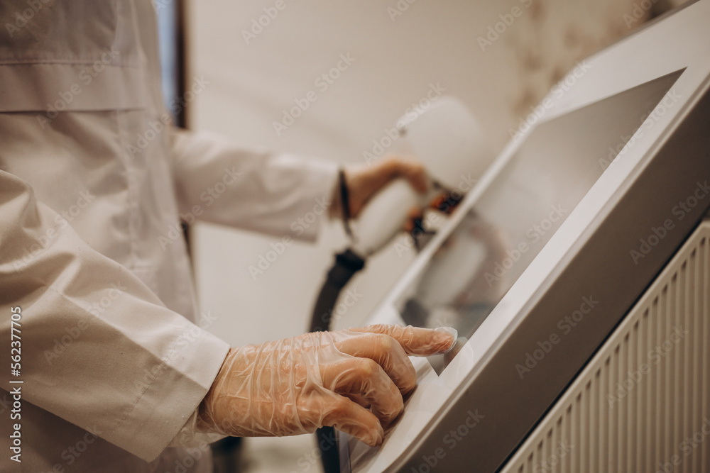 Obraz premium Cosmetologist's hand adjusting a modern laser apparatus in a beauty salon. Procedure of skin cleansing by laser pulses. The process of photothermolysis, warming the skin. Hardware