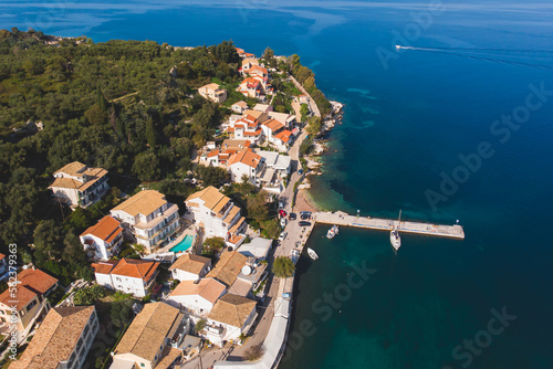 Aerial drone view of Kassiopi, village in northeast coast of Corfu island, Ionian Islands, Kerkyra, Greece in a summer sunny day, with marina, town, beach and castle photo