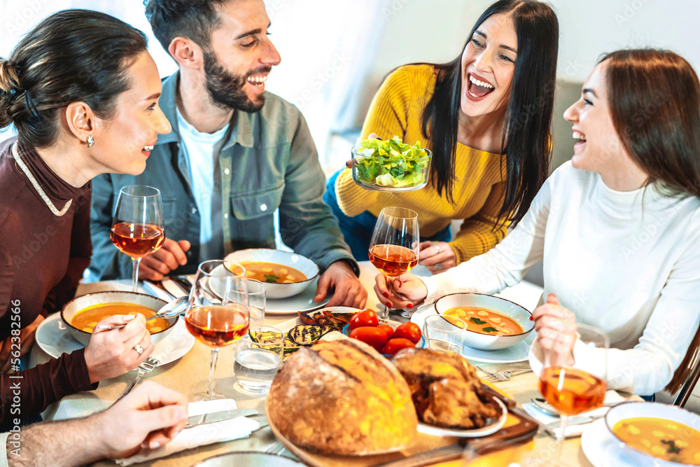 Group of smiling friends enjoying dinner at home - Happy family having dining party together - Life style concept with guys and girls eating meal and drinking red wine - Food and beverage lifestyle Group of smiling friends enjoying dinner at home - Happy family having dining party together - Life style concept with guys and girls eating meal and drinking red wine - Food and beverage lifestyle