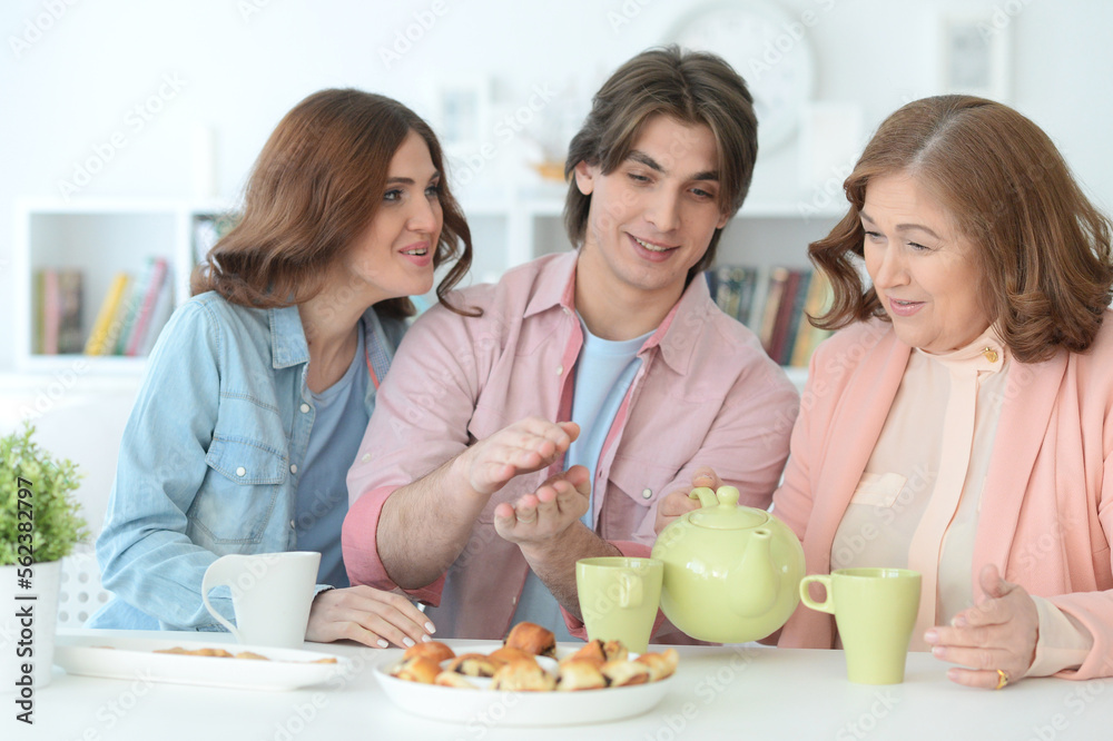 family of three spending time at dinner table with cookies and tea family of three spending time at dinner table with cookies and tea