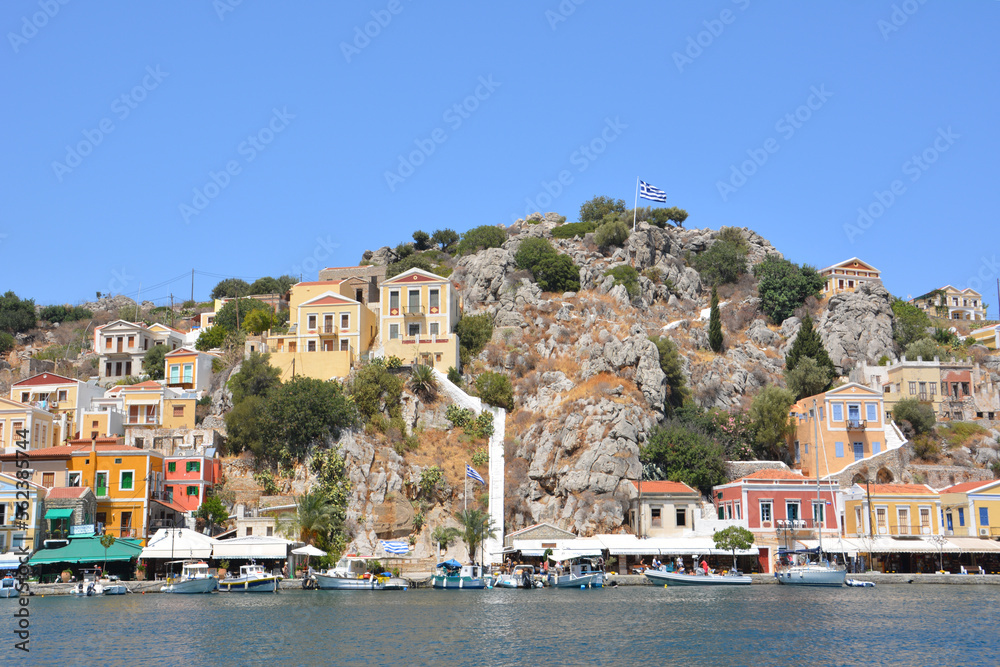greek island Symi with multicolored houses, yachts and stair with blue sky on background 