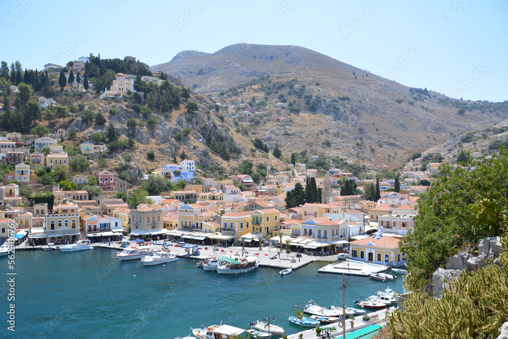 bay of water with boats and multicolored greek buildings of Symi island, topview