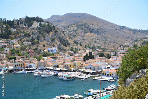 bay of water with boats and multicolored greek buildings of Symi island, topview