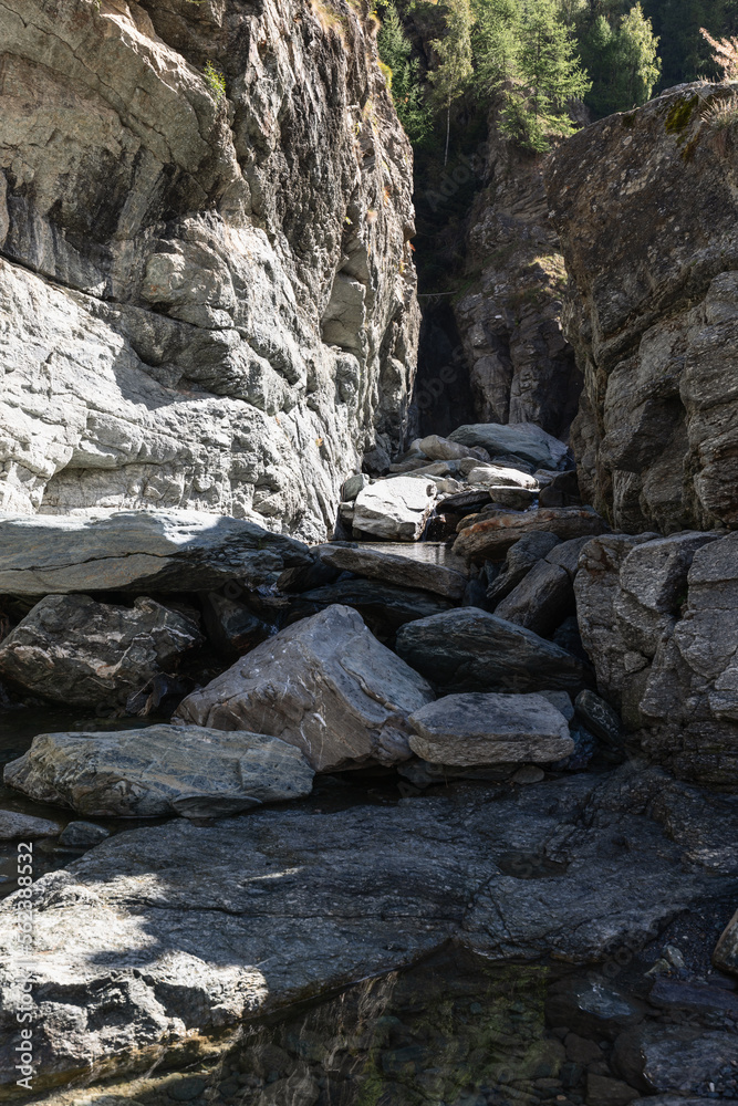 Bed of Lillaz waterfall (Cascate di Lillaz) divided by thousands of years of formation in granite alpine rocks, dried up this season with little pond. Aosta valley, Italy (vertical photo) Bed of Lillaz waterfall (Cascate di Lillaz) divided by thousands of years of formation in granite alpine rocks, dried up this season with little pond. Aosta valley, Italy (vertical photo)