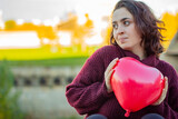 Mujer joven de raza caucásica con el pelo corto agarrando un globo rojo con forma de corazón que le han regalado por el día de san valentín.