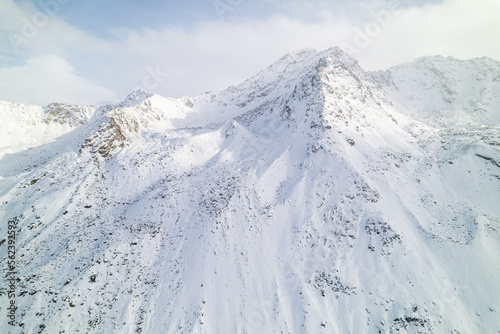 Snow covered peaks of mountains during winter on a sunny day with clouds in Fluela Pass, Davos, Switzerland.