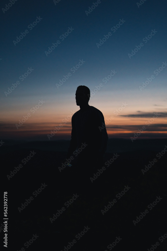 Silhouette of a man during sunset with orange and blue sky. Silhouette of a man during sunset with orange and blue sky.