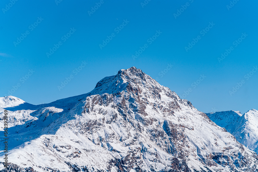 Mountain peak with rocks covered in snow during winter on a sunny day in Switzerland.