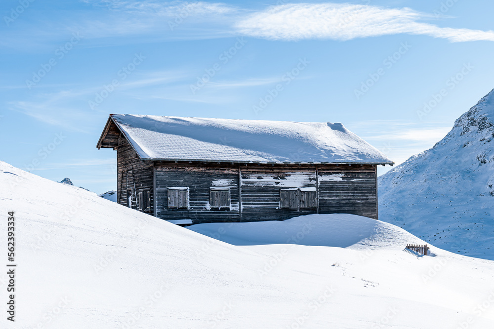 Detail of a wooden cabin in the mountains during winter covered in fresh snow on a sunny day in Switzerland.