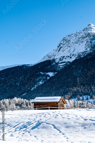 Wooden hut in between mountains covered in snow during winter on a sunny day in Switzerland. © Patrick Pimienta